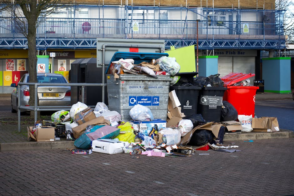A person wearing a white T-shirt with the text 'NO PLANT B' and white gloves is holding a transparent plastic bag filled with various waste items, including paper and possibly packaging, with a blue d